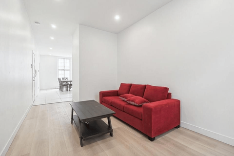 Canapé rouge et table basse noire dans un salon aux murs blancs avec parquet en bois clair.