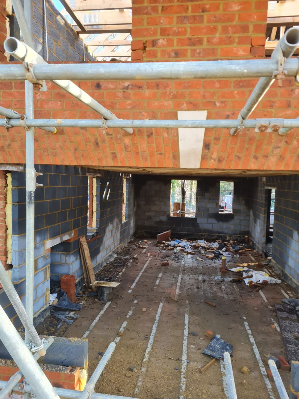 Interior of a building under construction, showing exposed brick, cinder blocks, and scaffolding.