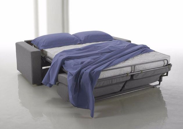 Divano-letto elegante in un soggiorno luminoso con sistema di apertura visibile e rivestimento chiaro.