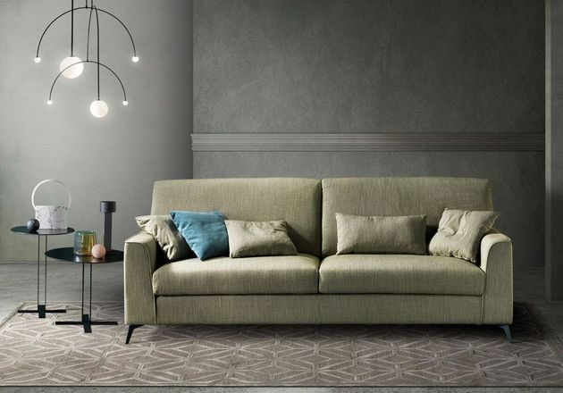 Divano lineare elegante in tessuto chiaro in uno showroom luminoso.