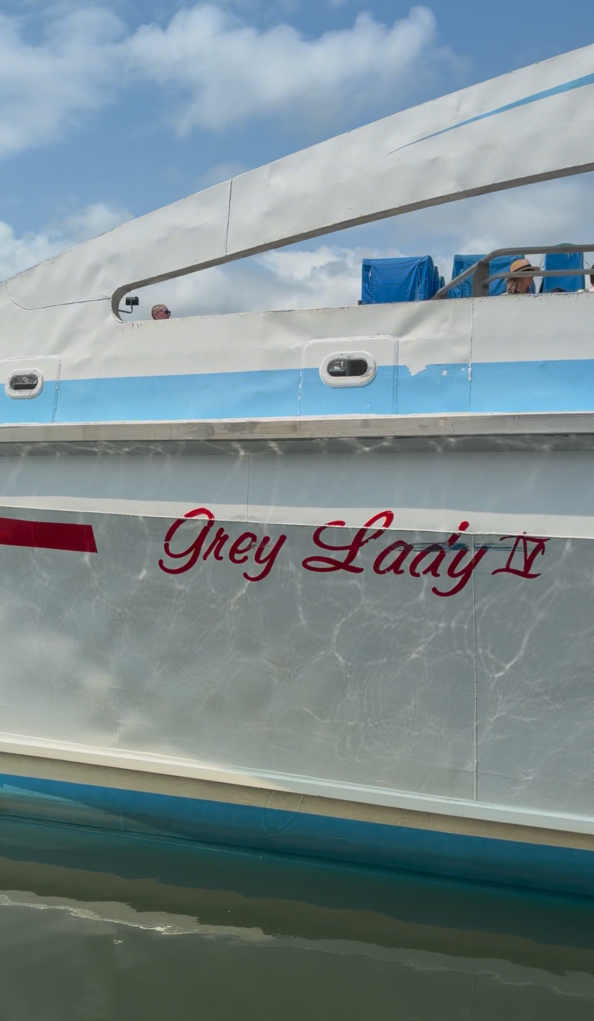 Side view of a silver boat named “Grey Lady II” on calm water under a blue sky