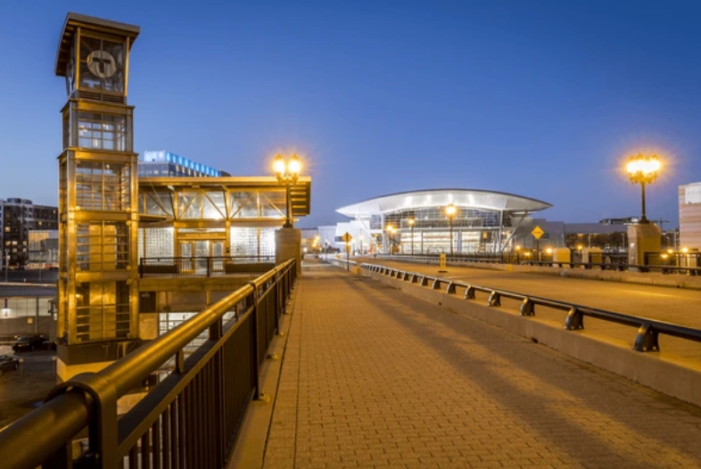 A bridge leading to a building with a clock tower in the background.