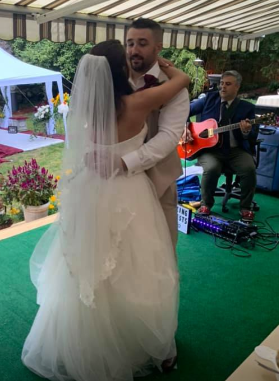A bride and groom are dancing in front of a man playing a guitar.