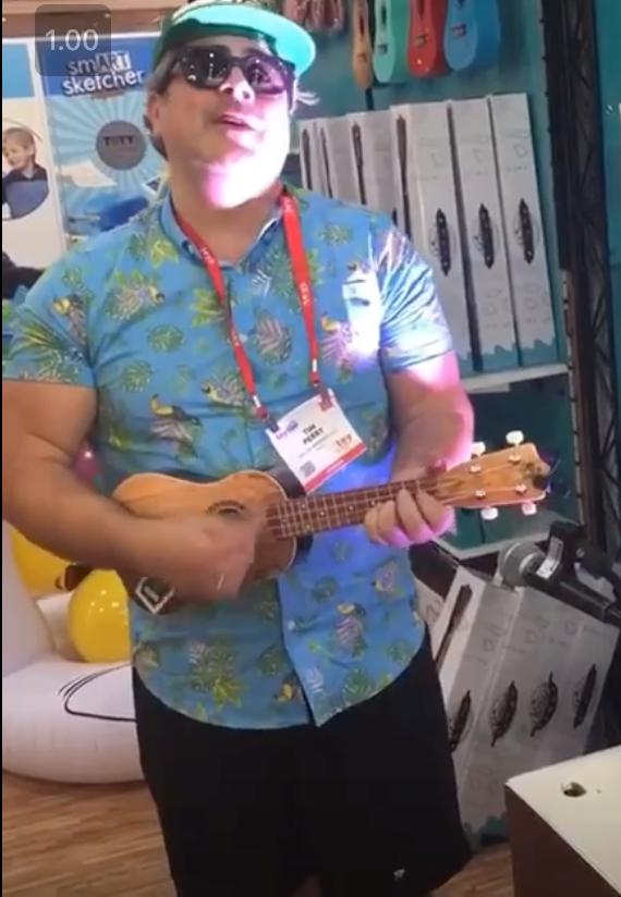 A man in a blue shirt is playing an ukulele
