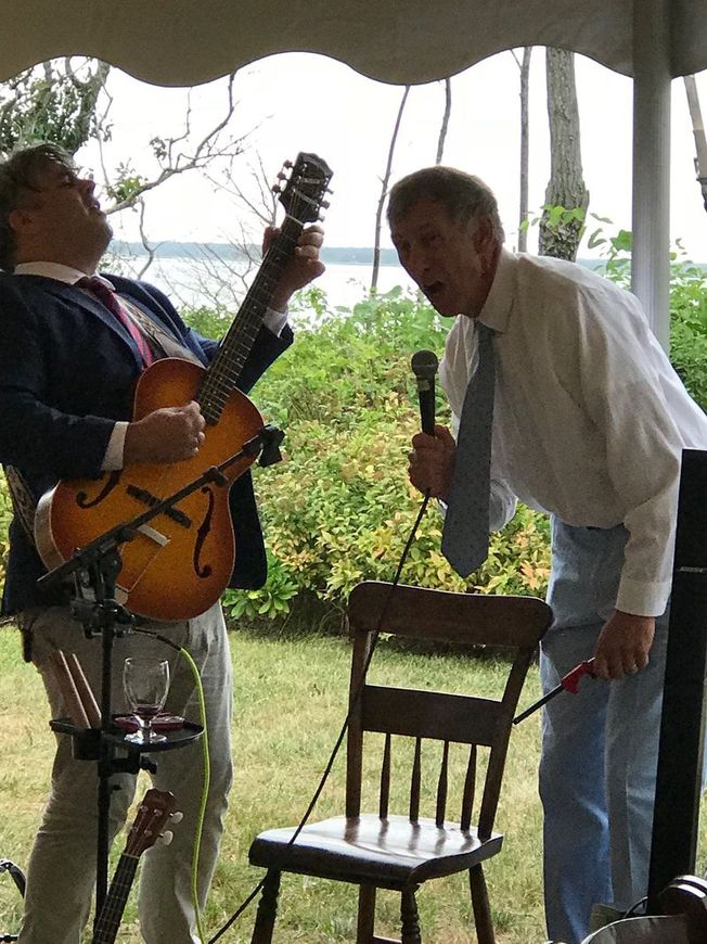 A man playing a guitar and another man singing into a microphone