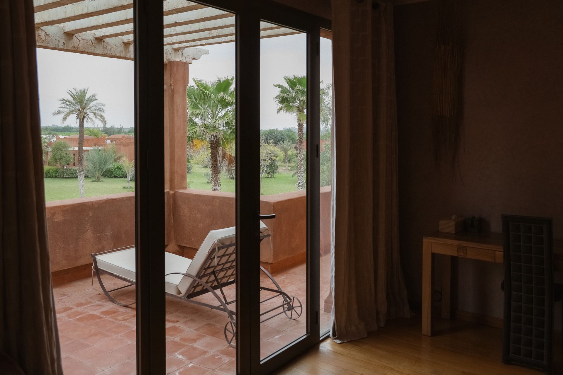 Chambre ouvrant par une baie vitrée sur les jardins et les palmiers à Bab Akoul Atlas