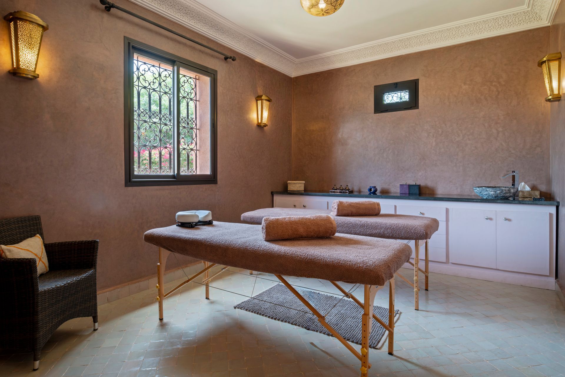 Massage room with two treatment tables, beige walls, and soft lighting