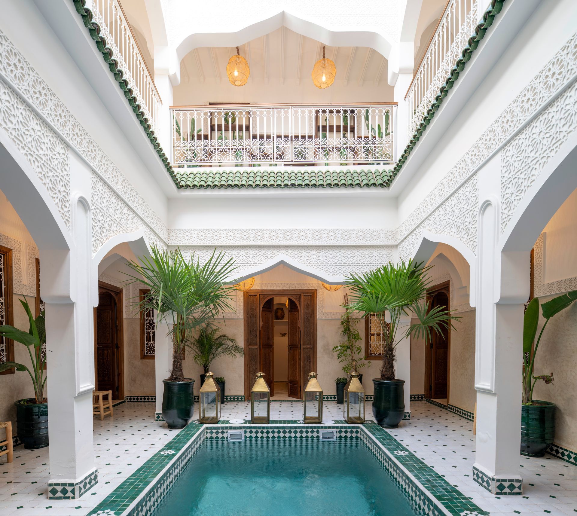 Elegant white courtyard with arches and a small turquoise pool inside a Moroccan-style riad