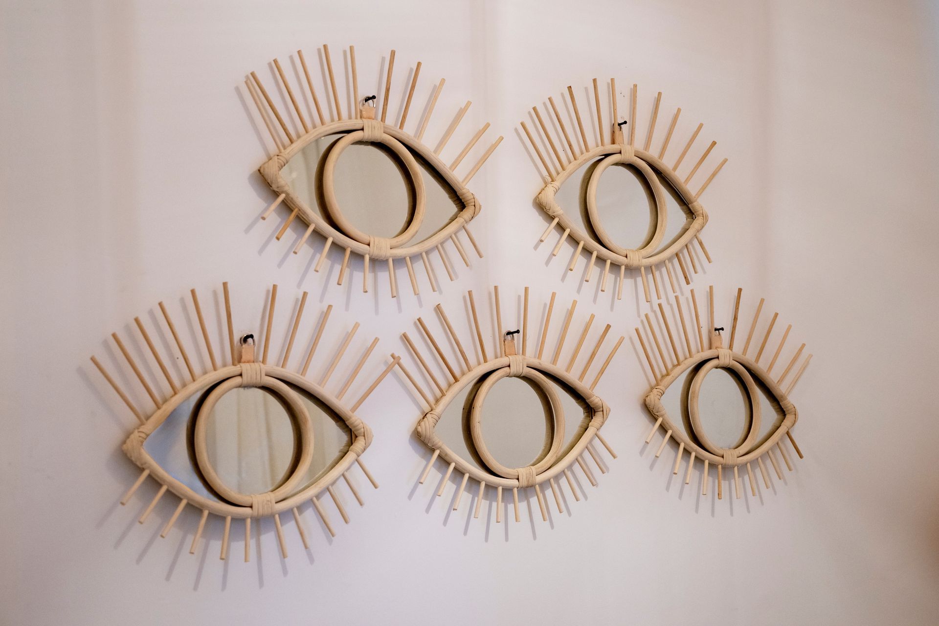 Five handmade eye wall hangings made of gold thread on a light background
