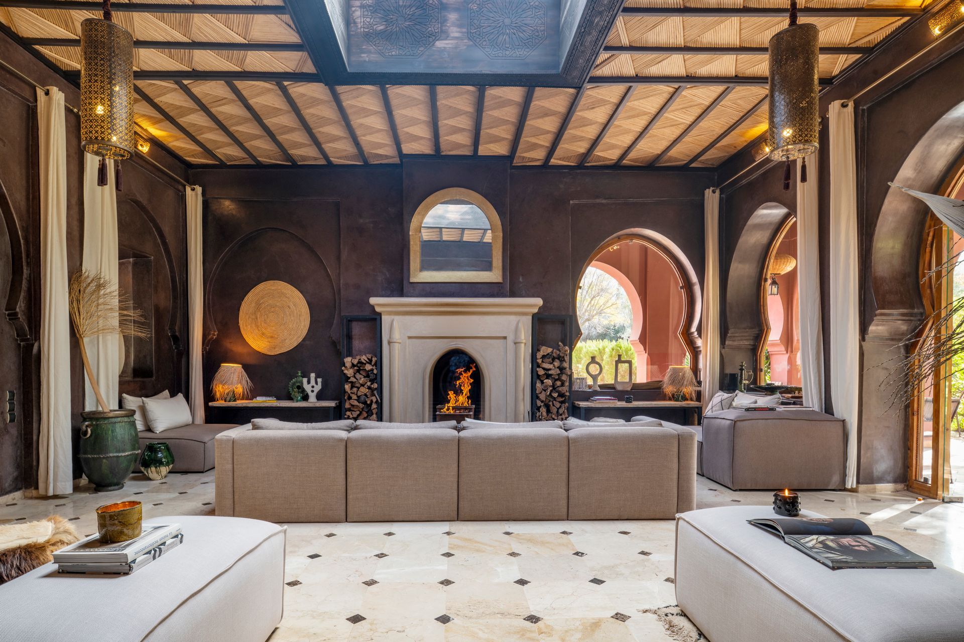 Elegant living room with fireplace, arched windows, white sofas, and warm earthy decor