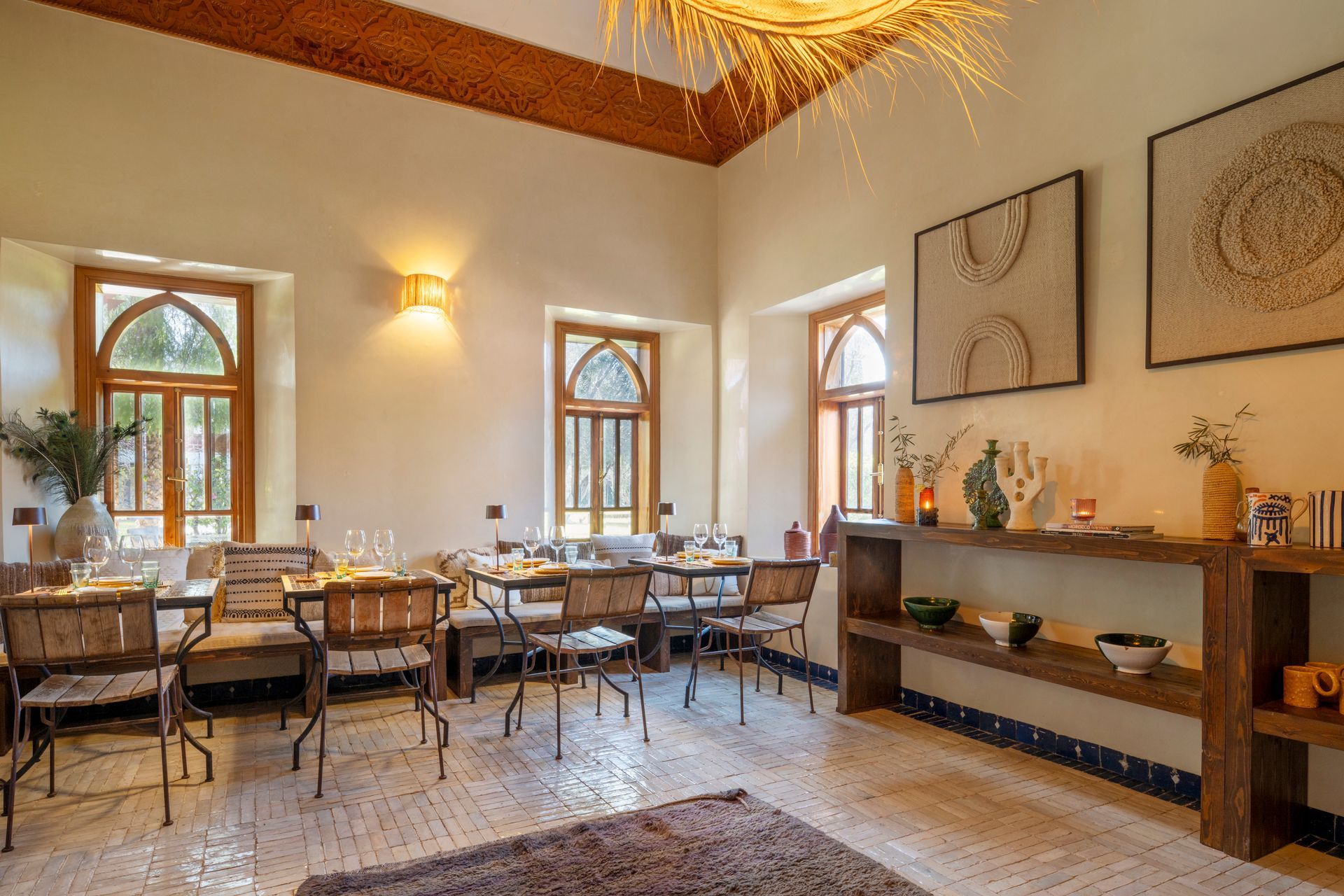 Elegant dining room with arched windows, set tables, and warm wall sconces
