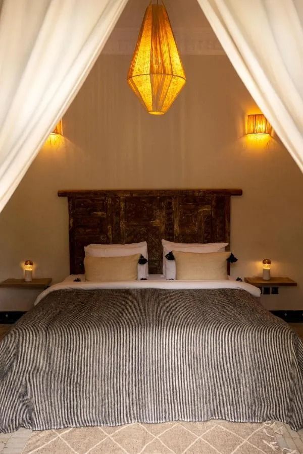 Neatly made bed with white pillows, folded blanket, and dark upholstered frame in a modern bedroom
