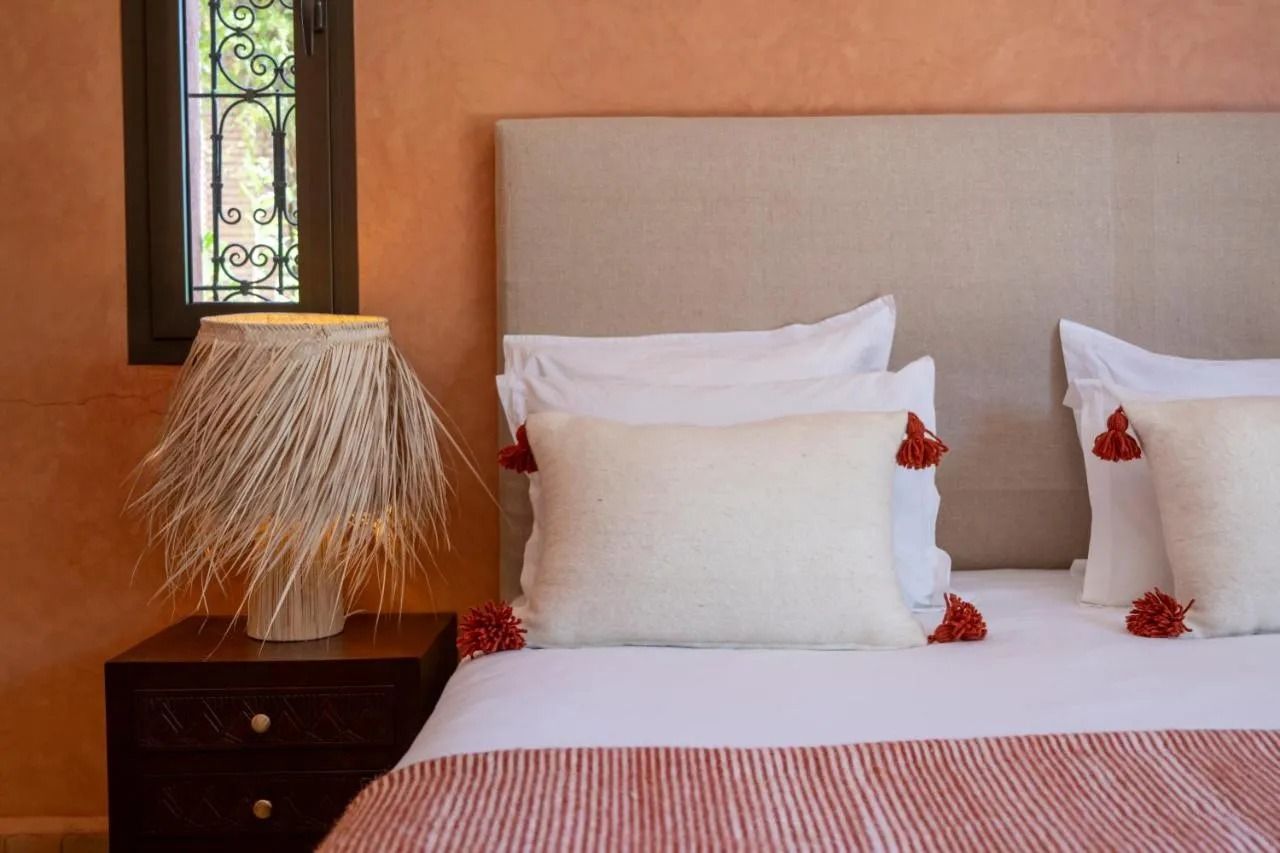 Sunlit bedroom with peach walls, open glass doors, a bed, and a patio view of greenery