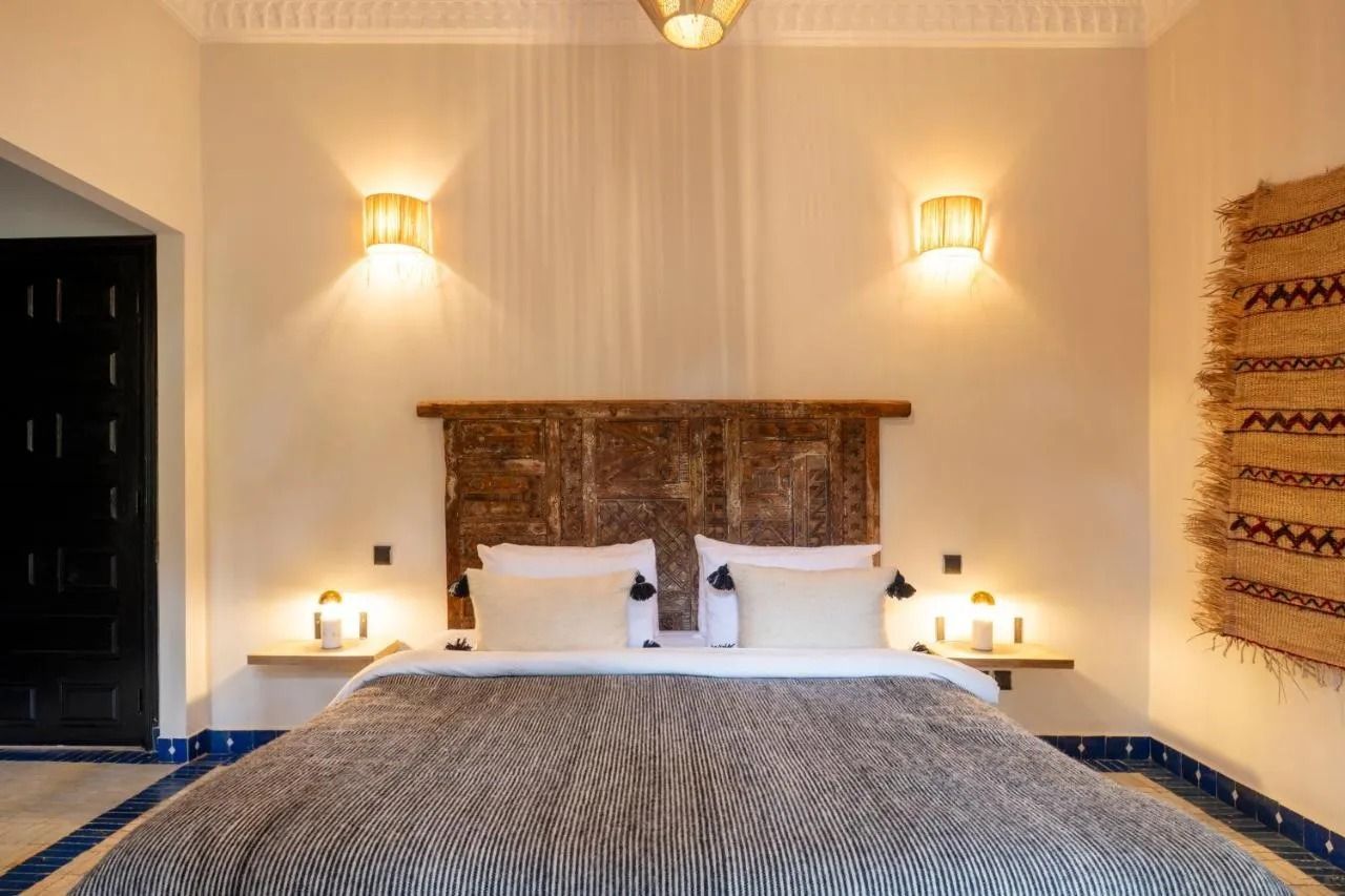 Cozy bedroom with large bed, woven headboard, wall sconces, and warm beige decor