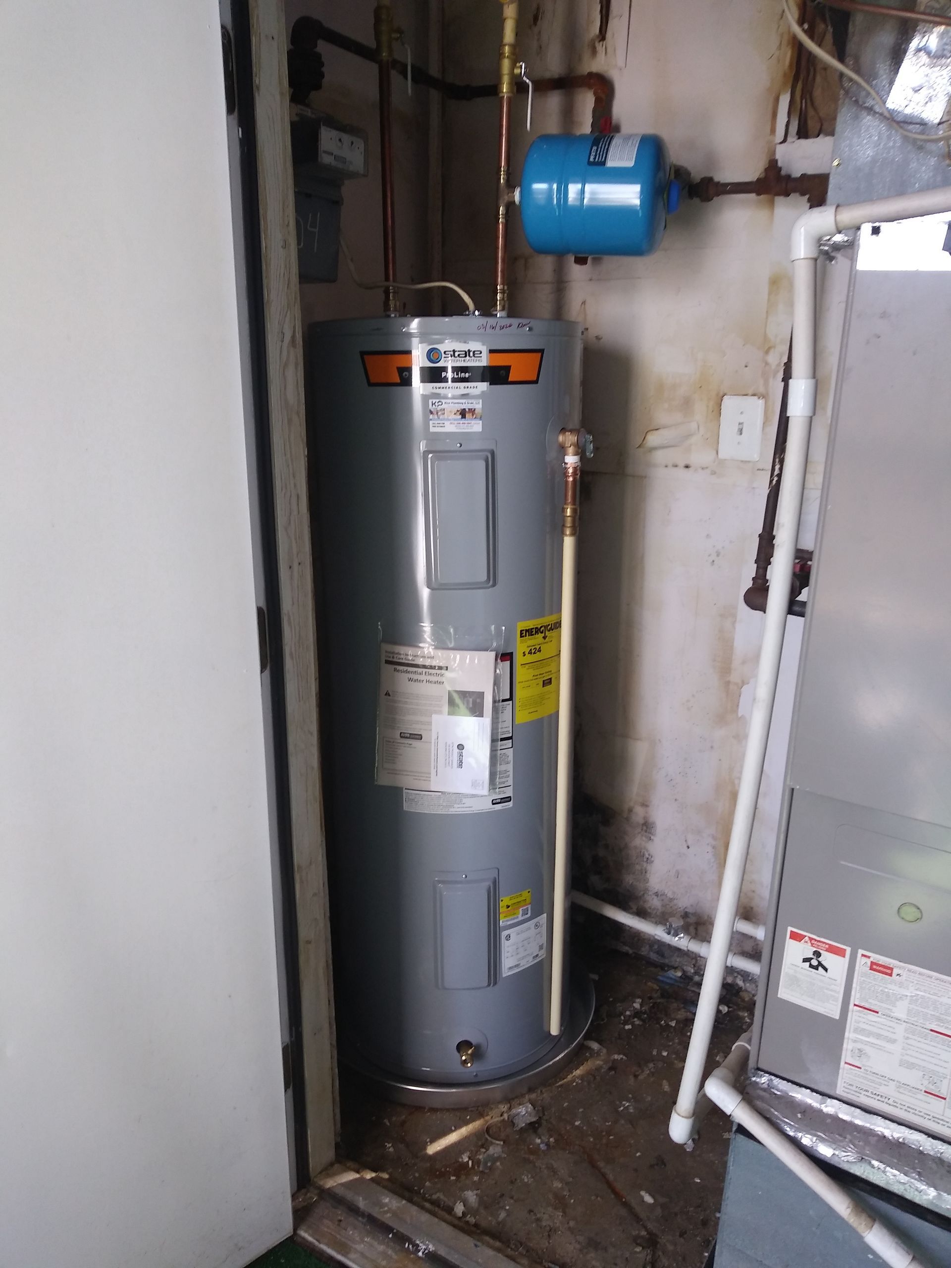 electric water heater base Corner of basement with a metal base for a new electric water heater on the floor near a doorway