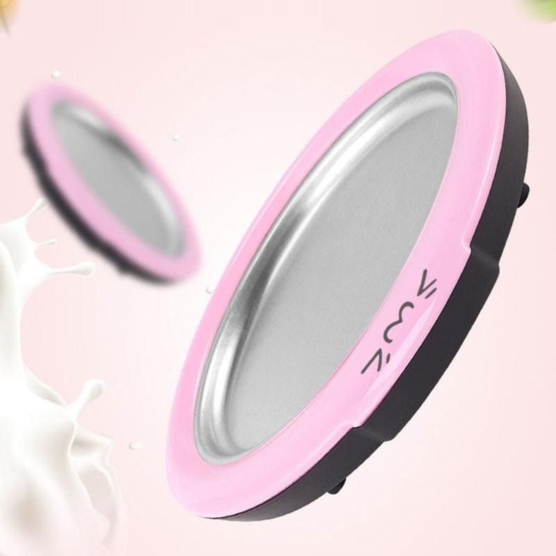 A pink and black ice cream roll maker with a stainless steel surface and two matching pink spatulas.