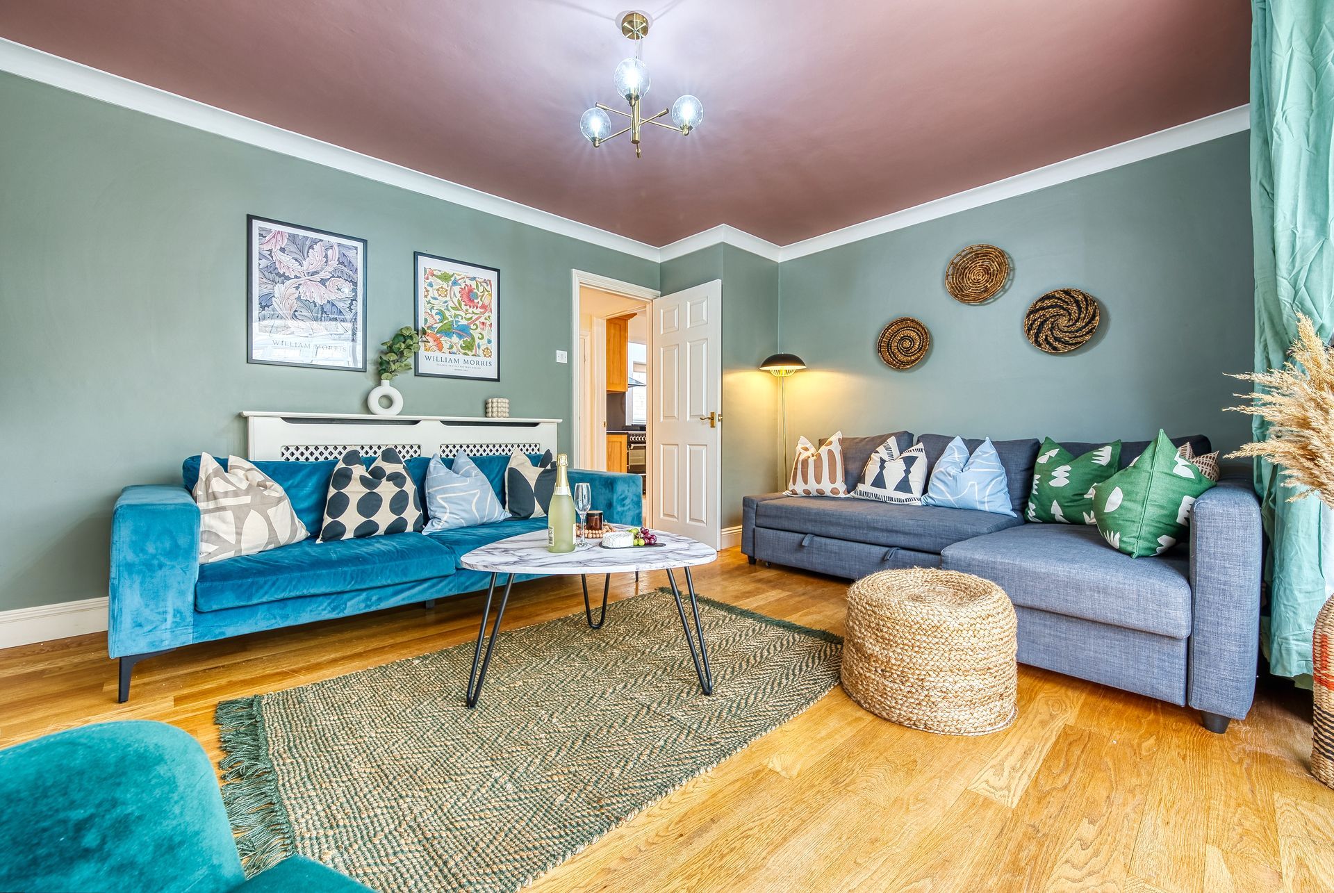 Living room with blue and gray sofas, green walls, and a burgundy ceiling.