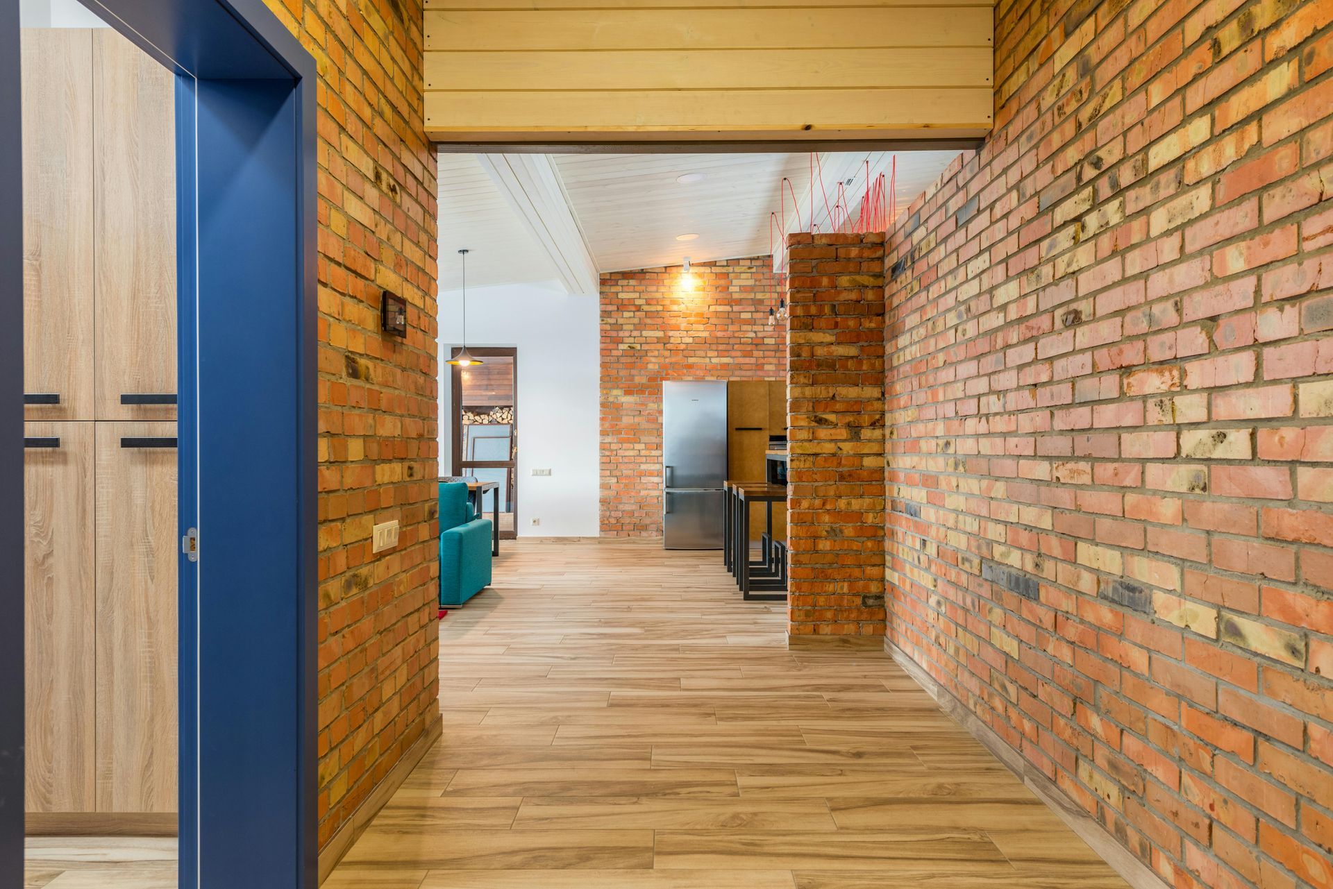 A hallway with a brick wall and wooden floor leading to a kitchen. Jarvis & Son Renovations,
