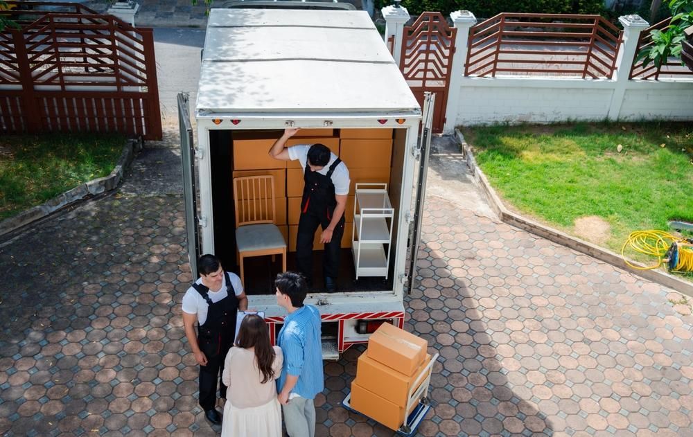 A Group Of People Are Standing In Front Of A Moving Truck — Ahern's Removals In Coffs Harbour, NSW