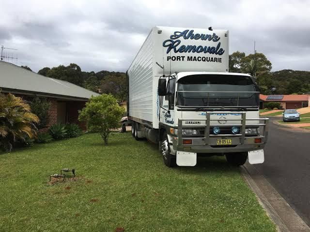 A Removal Truck Is Parked On The Side Of The Road In Front Of A House — Ahern's Removals In Laurieton, NSW
