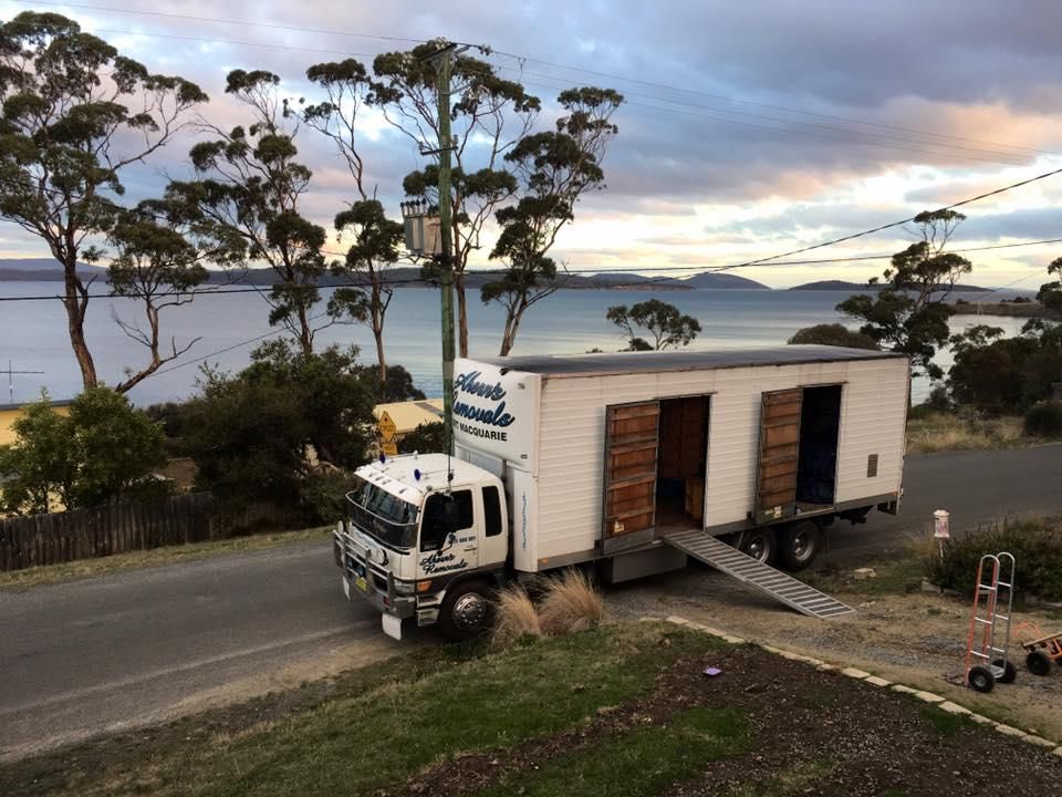 A Moving Truck Is Parked On The Side Of The Road Near A Body Of Water — Ahern's Removals In Port Macquarie, NSW