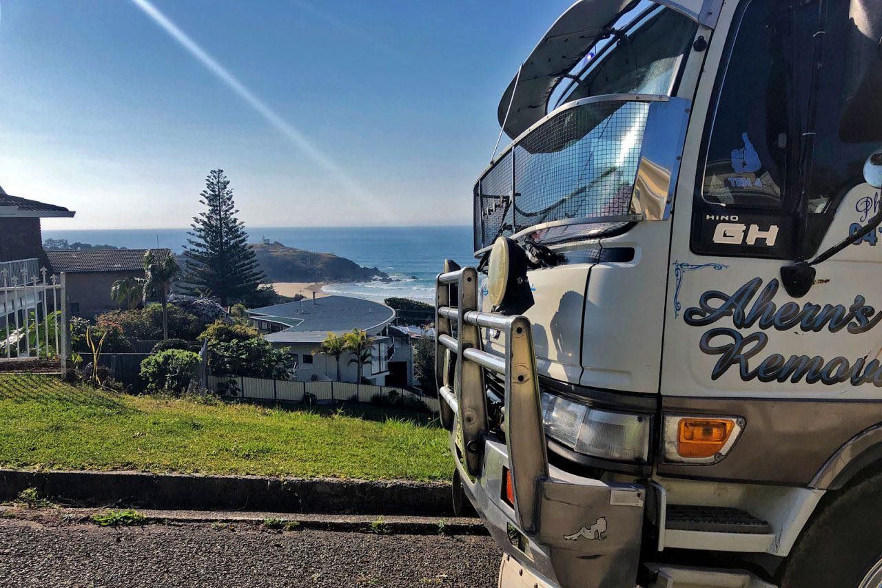 A White Truck Is Parked On The Side Of The Road With A View Of The Ocean — Ahern's Removals In Sydney, NSW