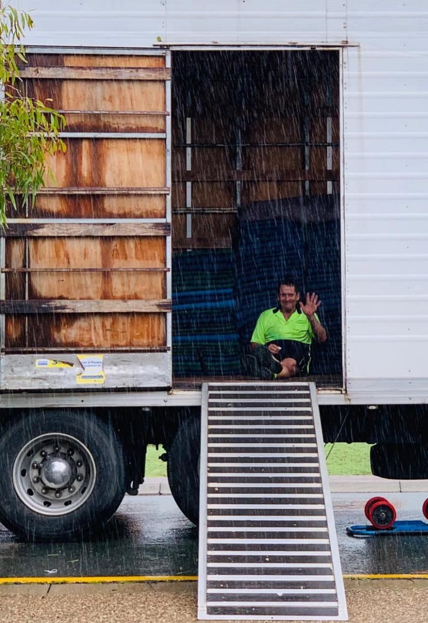 A Man Is Sitting In The Back Of A Truck In The Rain — Ahern's Removals In Canberra
