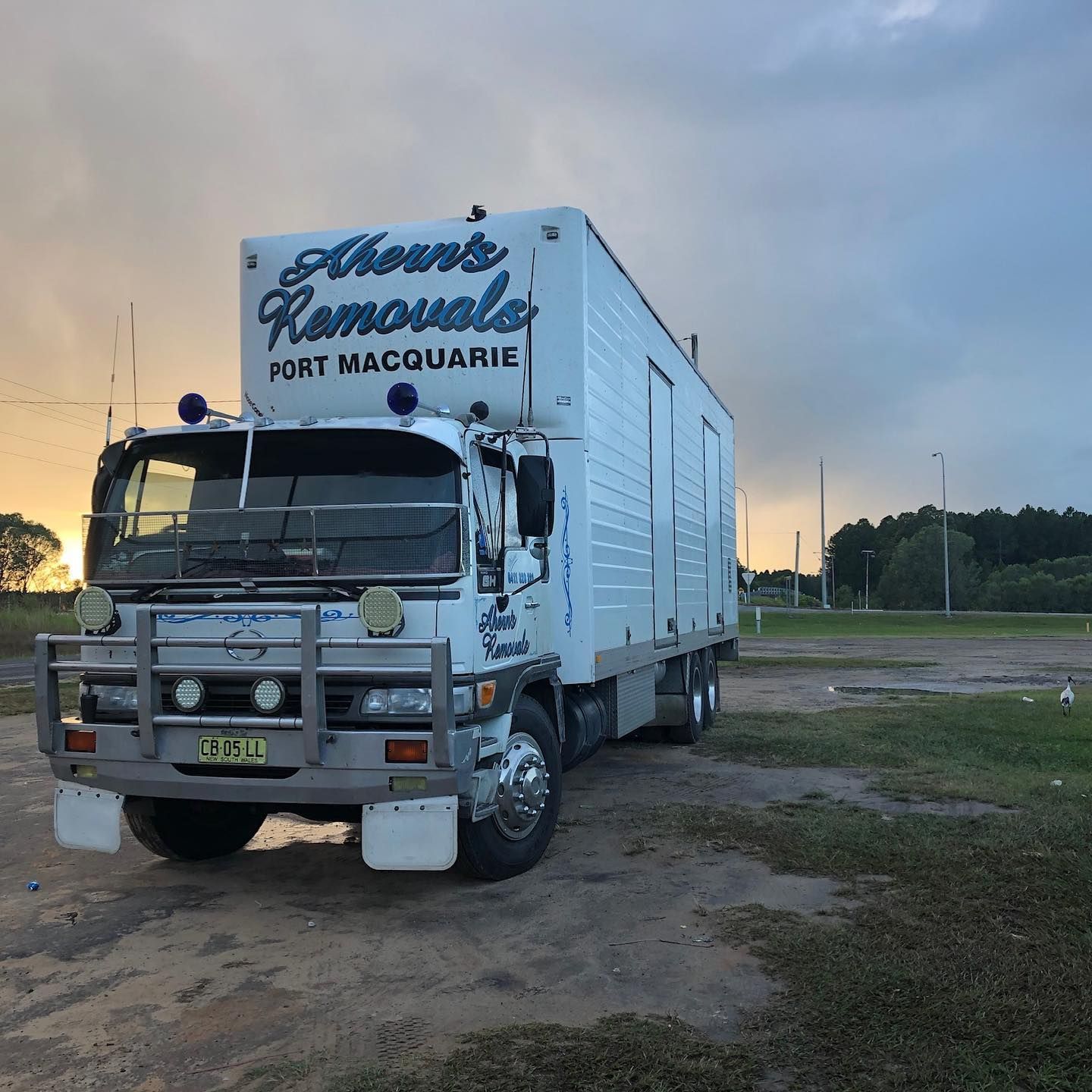 A House Removals Truck Is Parked In A Grassy Field — Ahern's Removals In South West Rocks, NSW