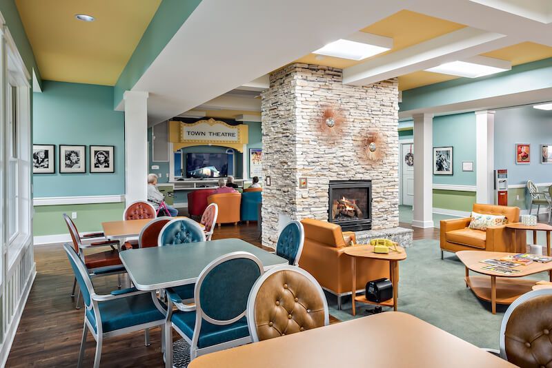 Cozy common room with fireplace, seating areas, and tables for residents.