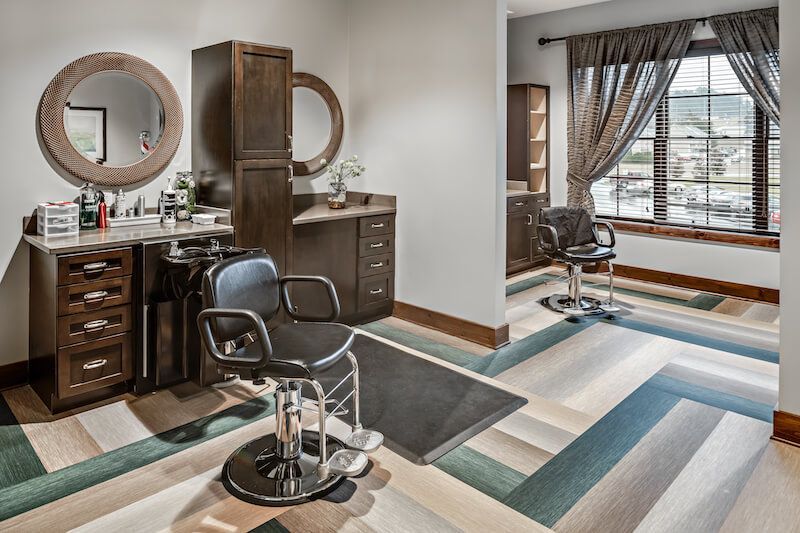 Hair salon with a black chair, two mirrors, and a window with city views.