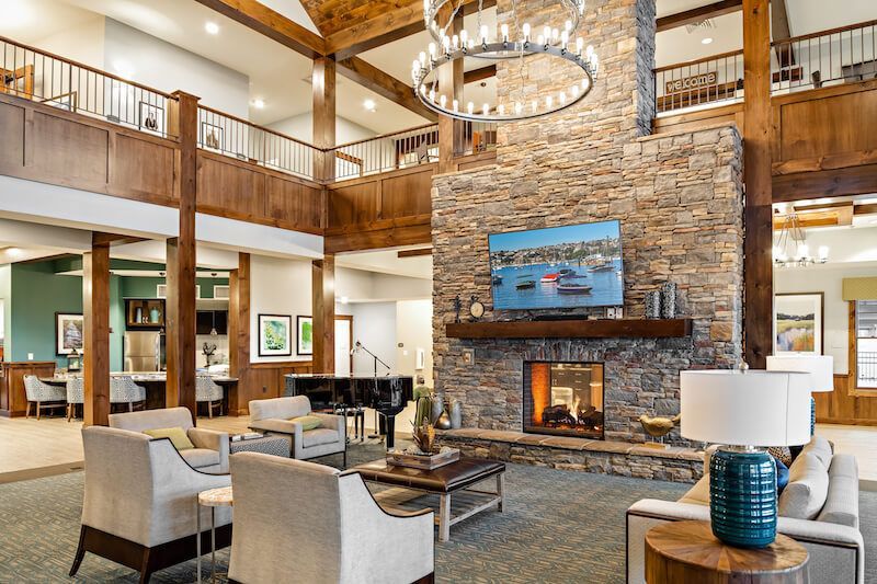 Lobby with fireplace, seating area, piano, and upper-level balconies; wood and stone accents.