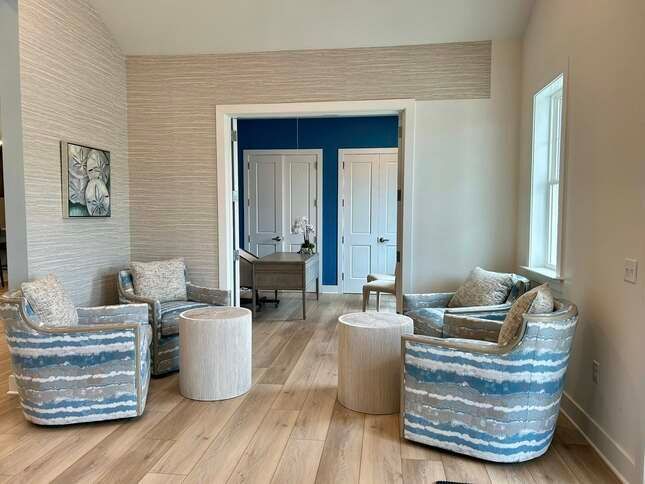 A living room with chairs and tables and a blue wall.