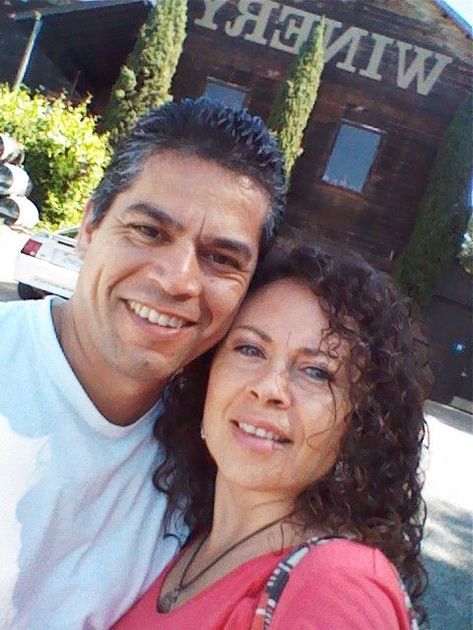 Two smiling people taking a selfie outside a building with a WINERY sign visible.