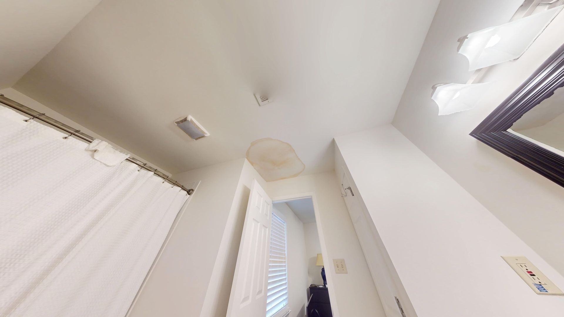 Water-stained and sagging bathroom ceiling damaged by a leak from the floor above in a Sandy Springs home