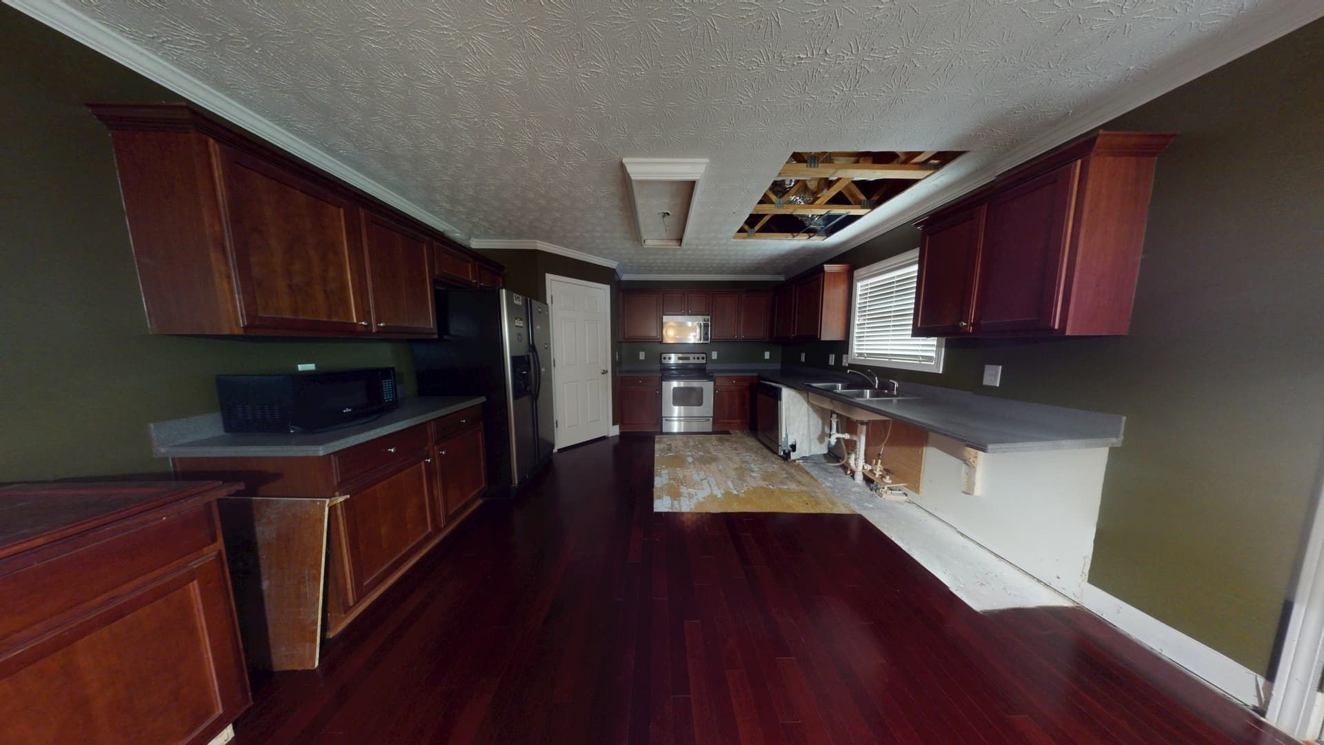 Second angle of Stonecrest kitchen flood showing water damage to flooring and cabinets