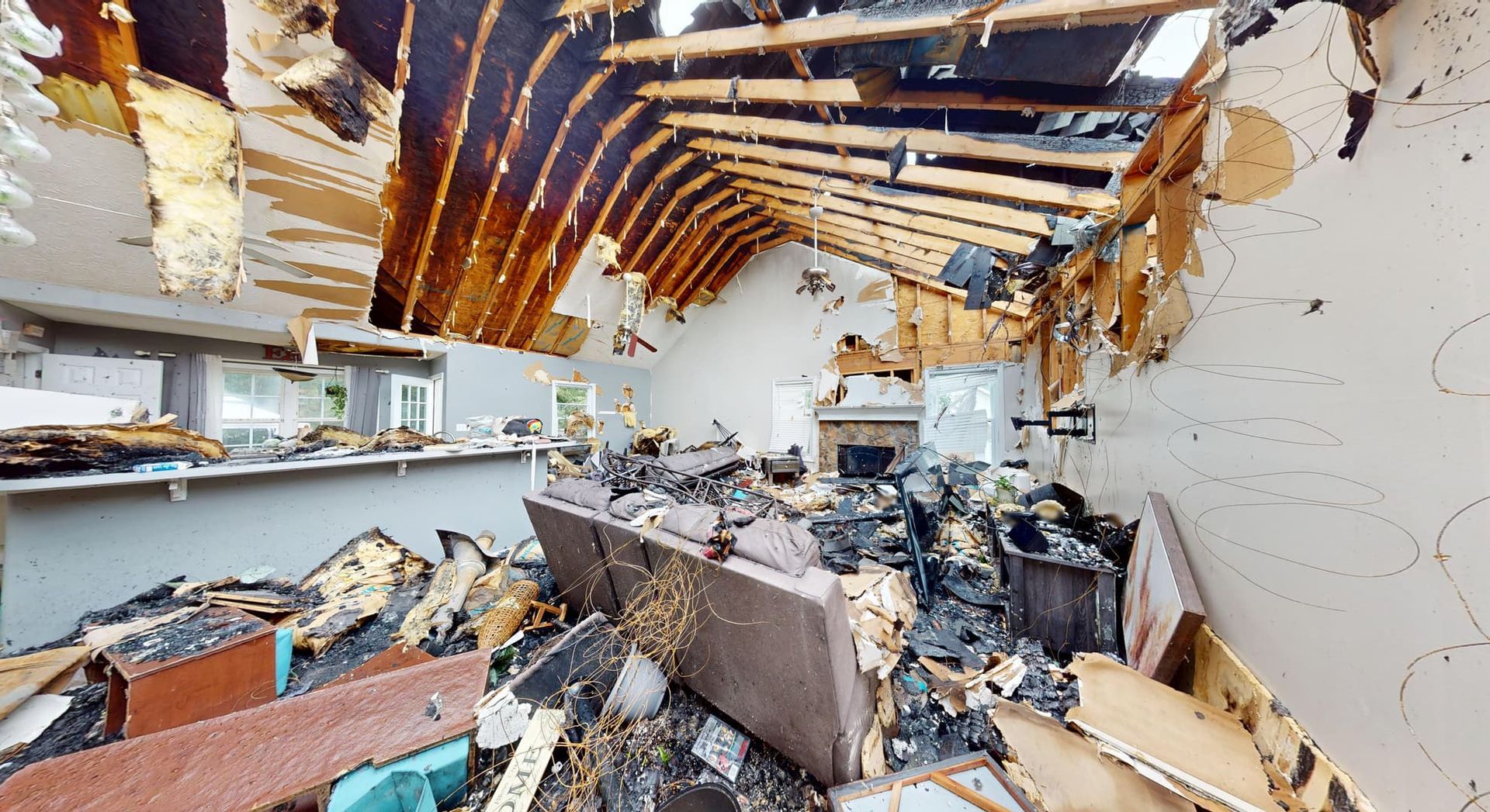 Fire damaged kitchen and dining room before restoration showing charred cabinets and warped countertops