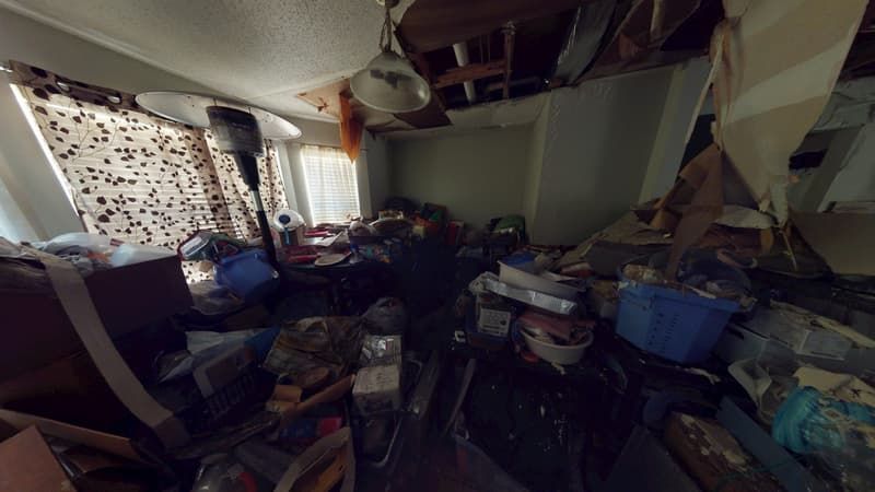 Kitchen area showing charred cabinets and soot-covered surfaces before cleanup