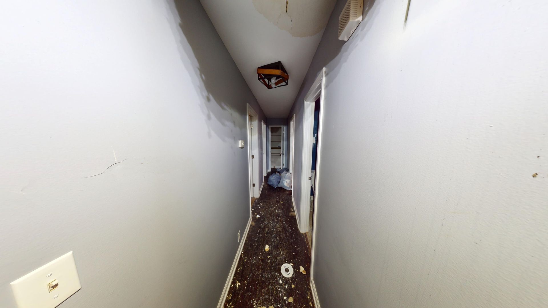 Hallway with water damaged walls and flooring before restoration in Stone Mountain