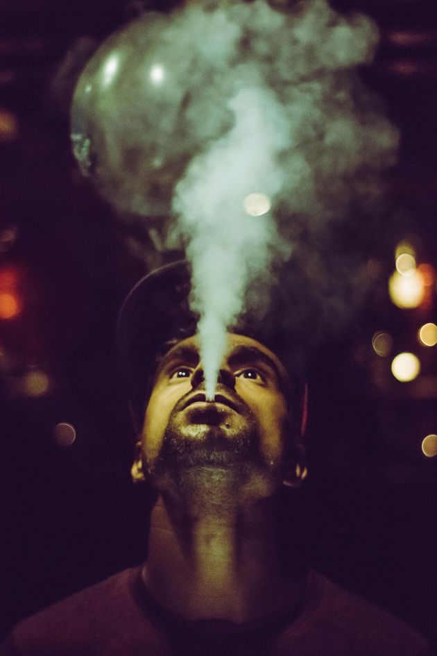 A man with a beard is blowing smoke out of his nose.