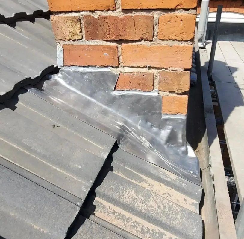 Lead flashing sealed to brick chimney on corrugated roof.