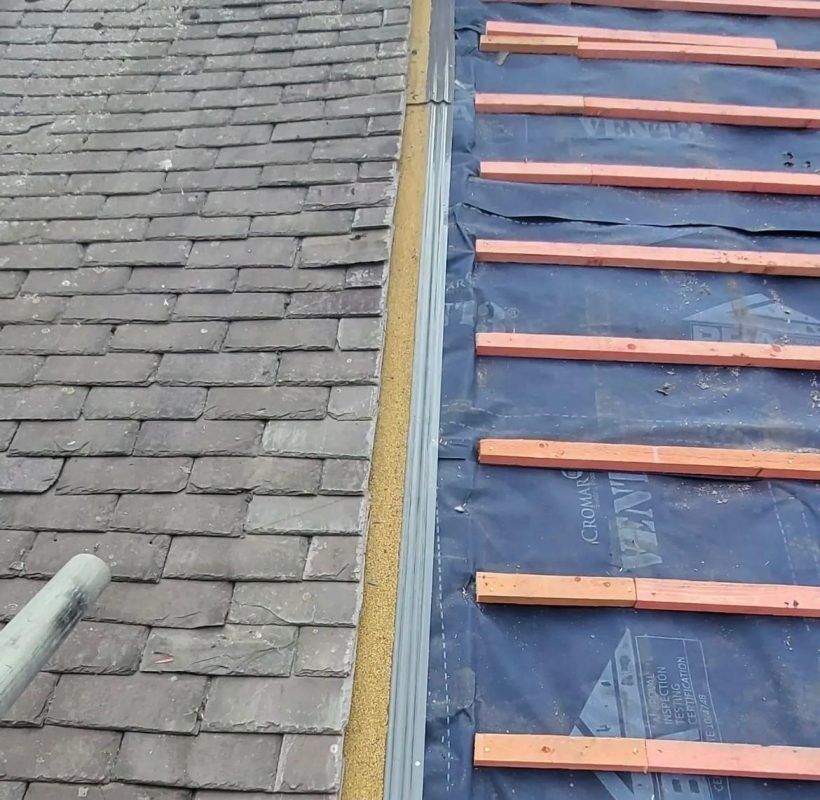 A roof transition showing installed slate shingles on the left and new wooden battens on roofing felt on the right.