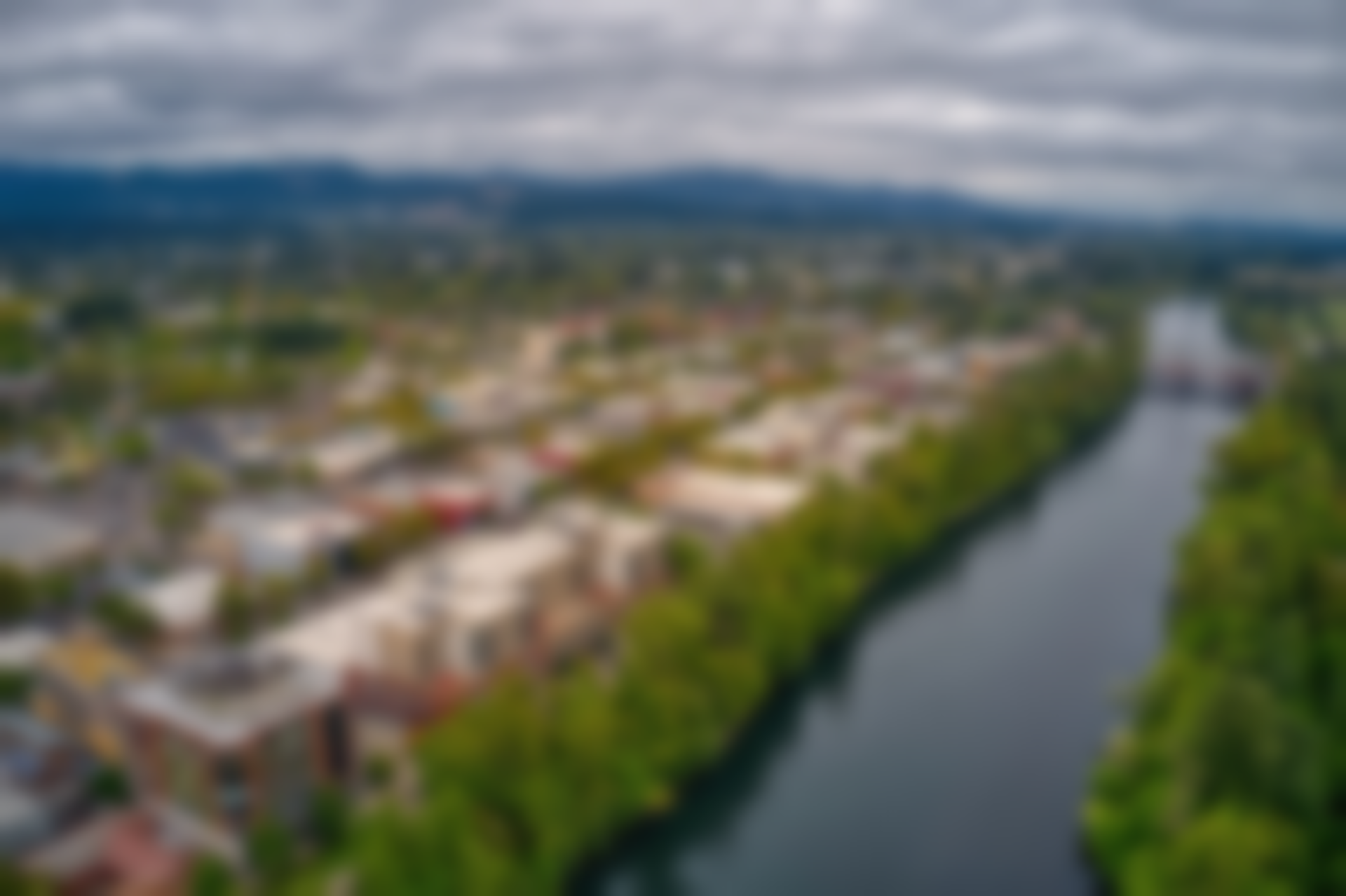 Aerial view of a town with a river running through it, under an overcast sky.