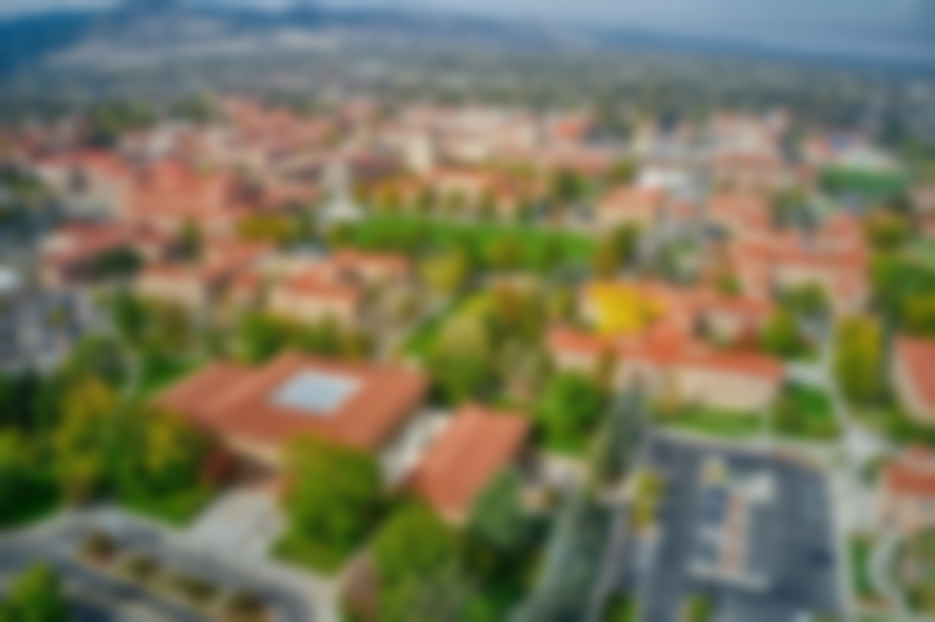 Aerial view of a campus with red-tiled roofs, green trees, and beige buildings.