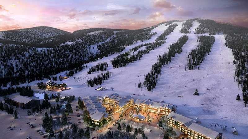 An aerial view of Cranmore ski resort surrounded by snow covered mountains.