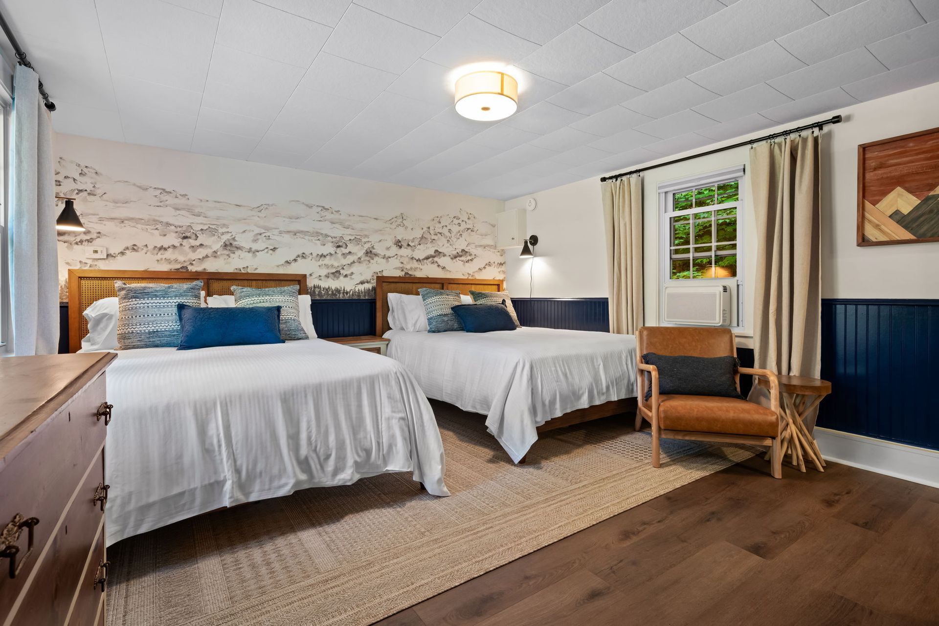 A hotel room with two beds and a chair.