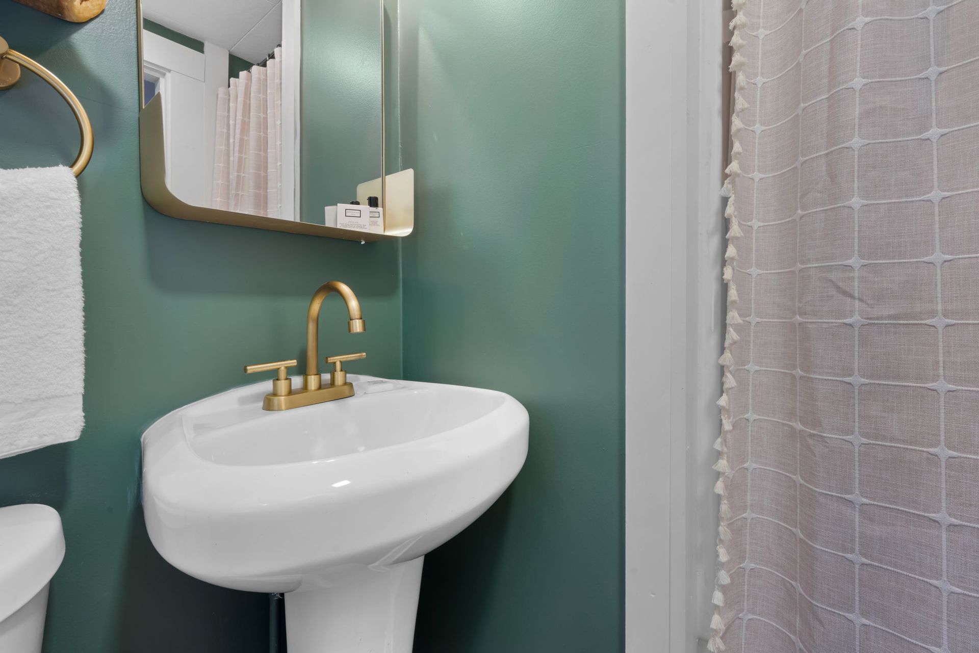 A bathroom with a sink , toilet , mirror and shower curtain.