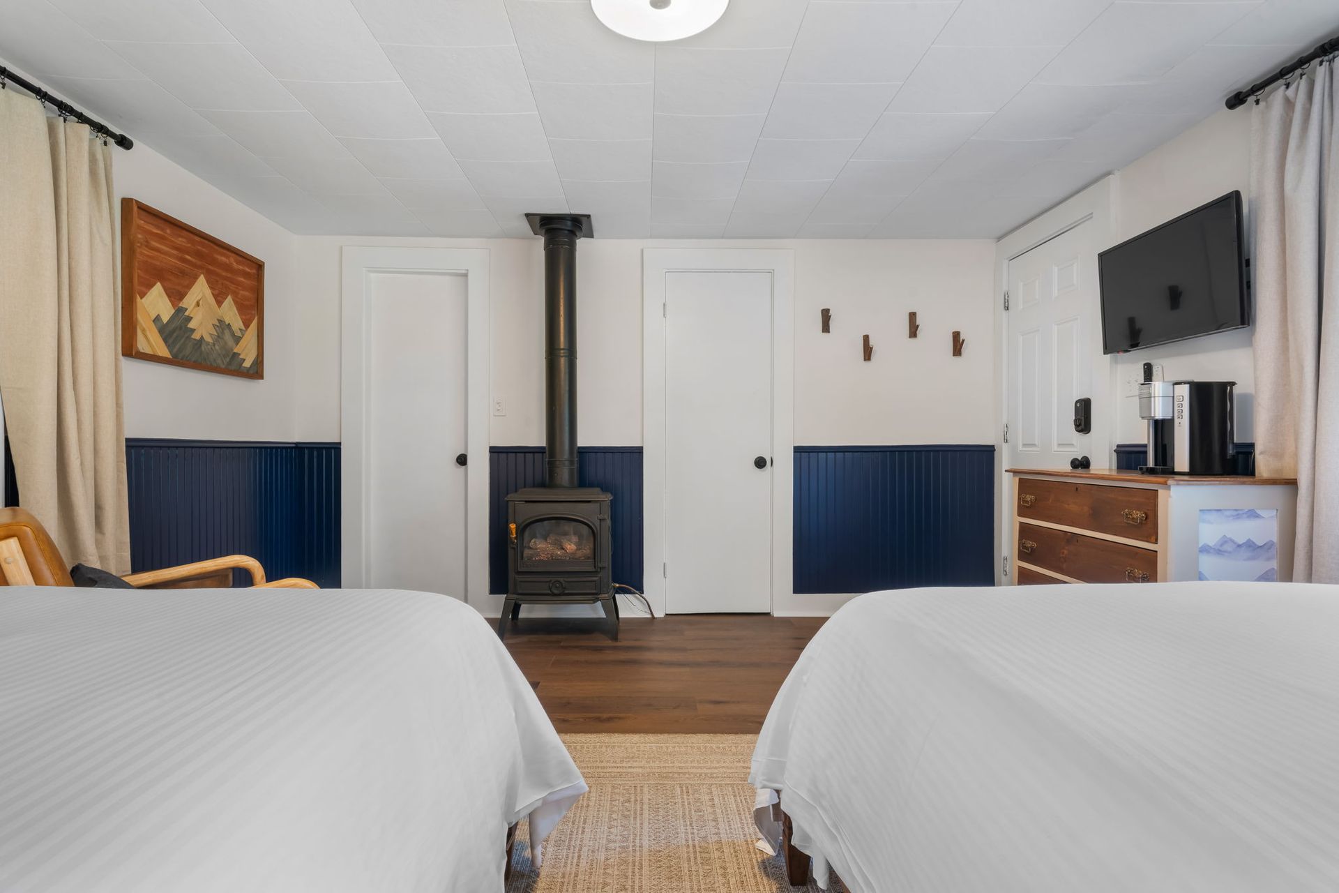 A hotel room with two beds and a wood stove.