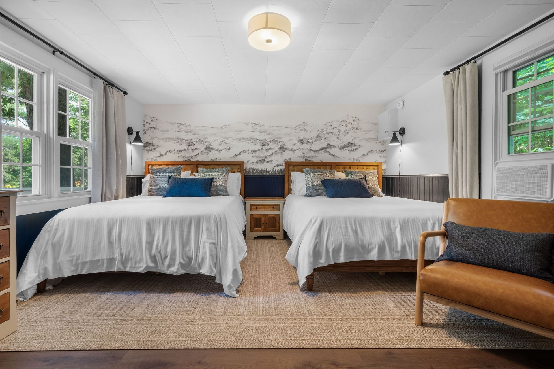 A hotel room with two beds and a chair.