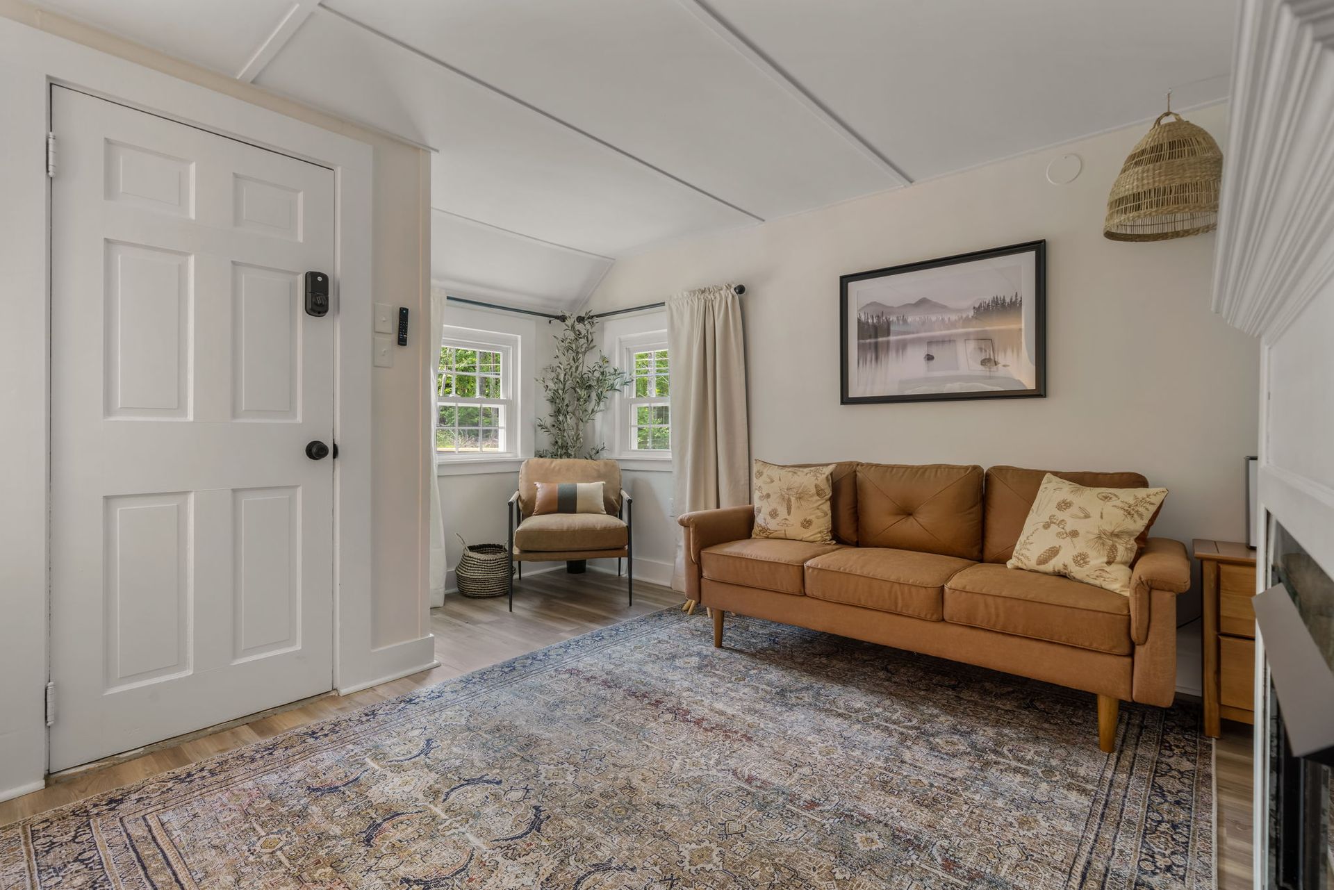 A living room with a couch , chair , rug and fireplace.