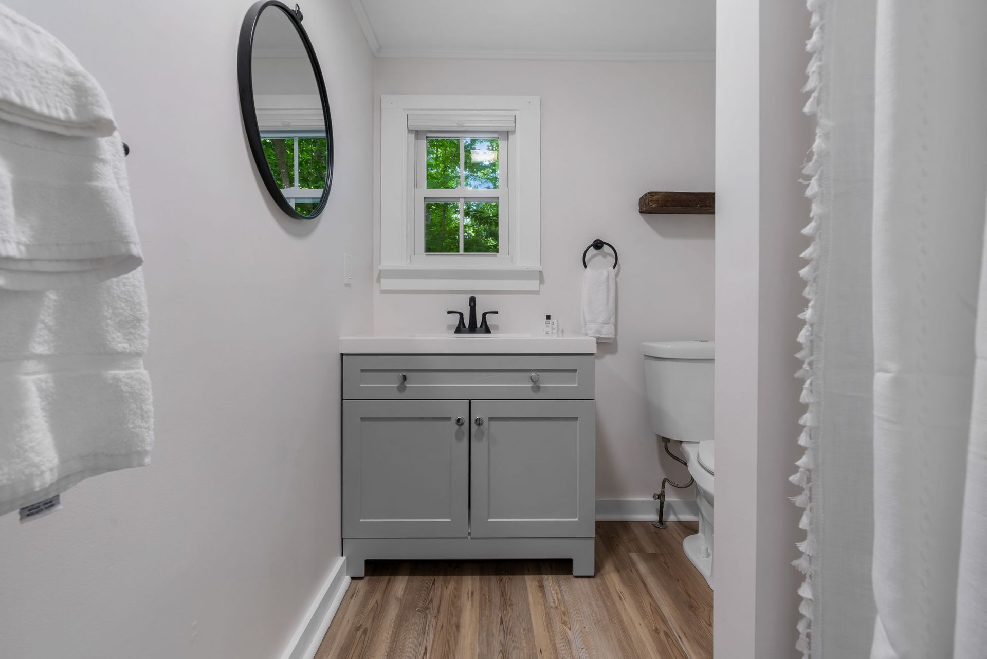 A bathroom with a sink , toilet , mirror and window.